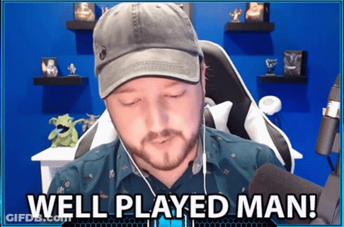 A Man Wearing A Hat And Ear Buds Is Sitting In Front Of A Microphone And Says Well Played Man GIF