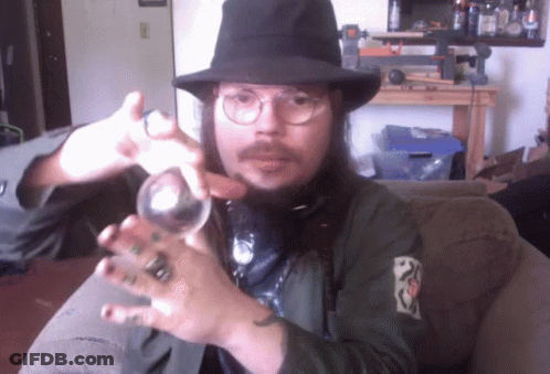 A Man Wearing A Hat And Glasses Is Holding A Glass Ball GIF