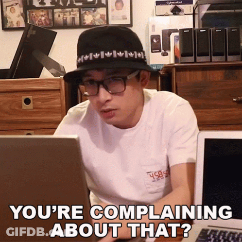 A Man Wearing A Hat And Glasses Is Sitting In Front Of A Laptop And Says You 'Re Complaining About That ? GIF