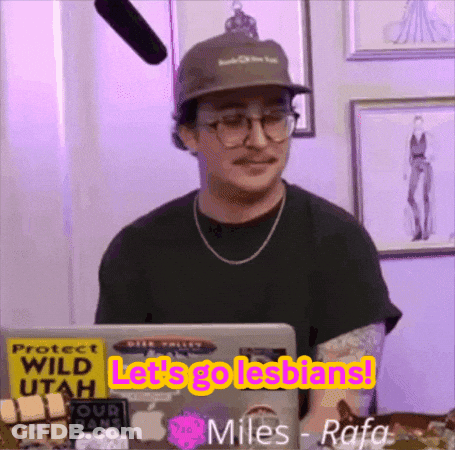 A Man Wearing A Hat And Glasses Is Sitting In Front Of A Laptop With The Words Let 'S Go Lesbians On It . GIF