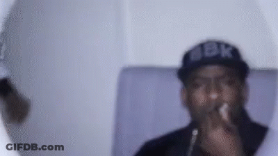 A Man Wearing A Hat And Glasses Is Smoking A Cigarette . GIF