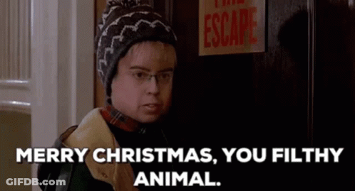 A Man Wearing A Hat And Glasses Is Standing In Front Of A Door And Says Merry Christmas , You Filthy Animal GIF