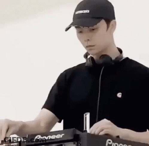A Man Wearing A Hat And Headphones Is Playing Music On A Dj Machine . GIF