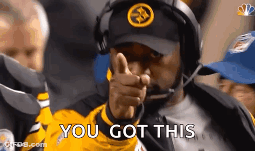 A Man Wearing A Hat And Headphones Is Pointing At The Camera . GIF