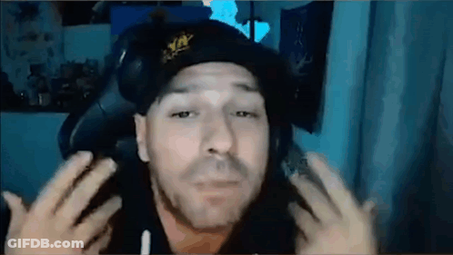 A Man Wearing A Hat And Headphones Is Sitting In A Chair And Making A Funny Face . GIF