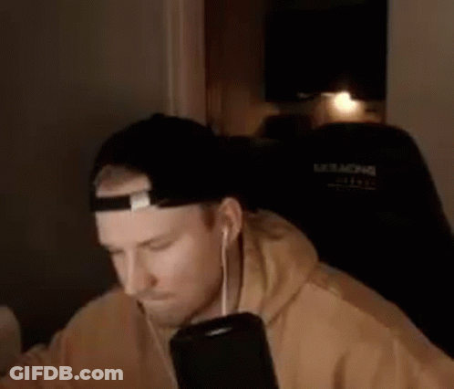 A Man Wearing A Hat And Headphones Is Sitting In A Chair . GIF