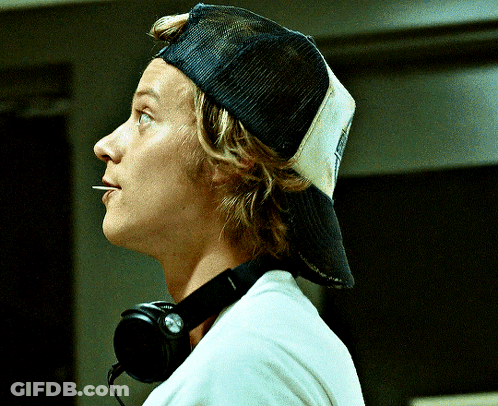 A Man Wearing A Hat And Headphones Looks To His Right GIF