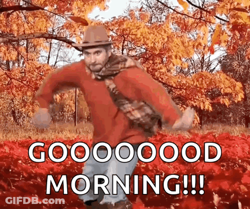A Man Wearing A Hat And Scarf Is Dancing In A Field Of Leaves And Says Good Morning ! GIF