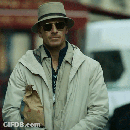 A Man Wearing A Hat And Sunglasses Is Holding A Bag Of Food GIF