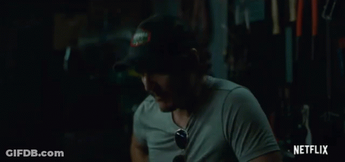 A Man Wearing A Hat And Sunglasses Is Sitting In A Dark Room With A Netflix Logo In The Corner . GIF