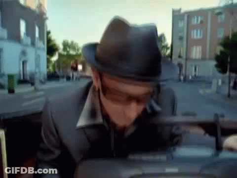 A Man Wearing A Hat And Sunglasses Is Sitting In The Back Seat Of A Car GIF