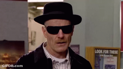 A Man Wearing A Hat And Sunglasses Is Standing In Front Of A Sign That Says `` Look For This '' . GIF