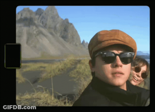 A Man Wearing A Hat And Sunglasses Stands Next To A Woman GIF
