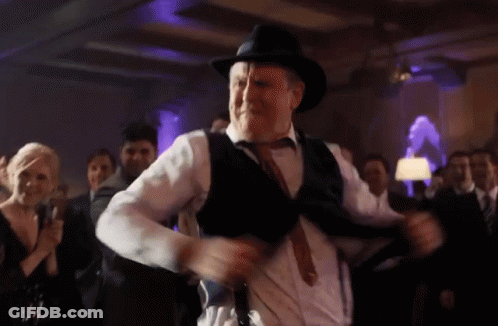 A Man Wearing A Hat And Suspenders Is Dancing At A Party GIF