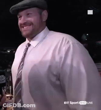 A Man Wearing A Hat And Tie Is Smiling And Holding A Glass Of Beer . GIF