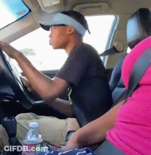 A Man Wearing A Hat And Visor Is Driving A Car Next To A Woman In A Pink Shirt GIF