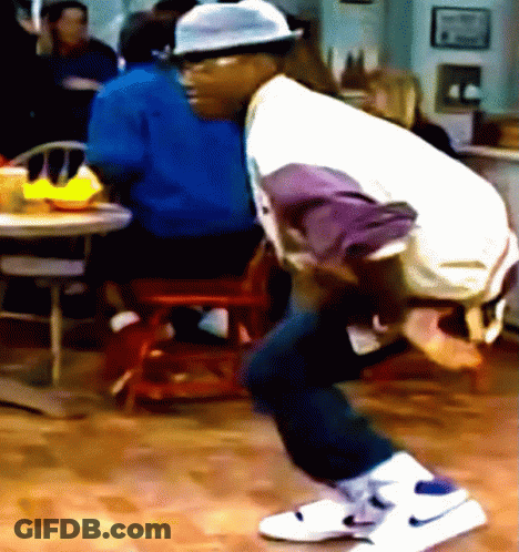 A Man Wearing A Hat And White Nike Shoes Is Squatting On The Floor GIF