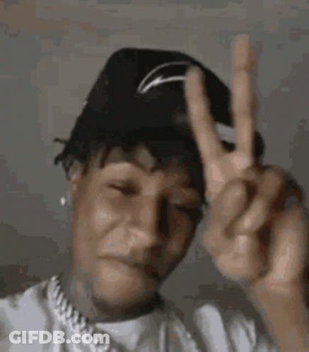 A Man Wearing A Hat Is Giving A Peace Sign . GIF