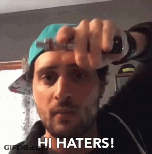 A Man Wearing A Hat Is Holding A Bottle And Saying Hi Haters GIF