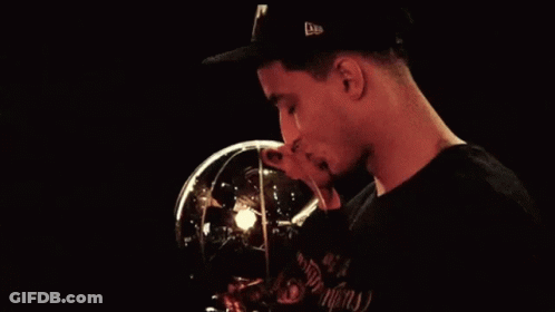 A Man Wearing A Hat Is Kissing A Trophy That Has The Letter N On It GIF