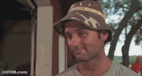 A Man Wearing A Hat Is Making A Funny Face And Smiling . GIF