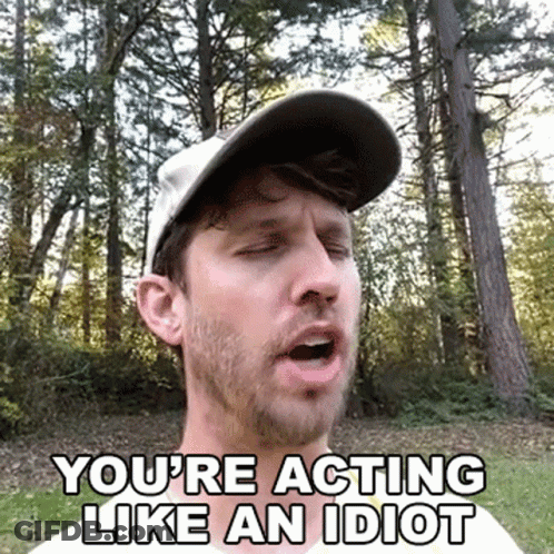 A Man Wearing A Hat Is Making A Funny Face While Standing In The Woods . GIF