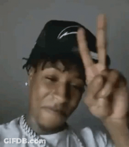 A Man Wearing A Hat Is Making A Peace Sign With His Hands . GIF