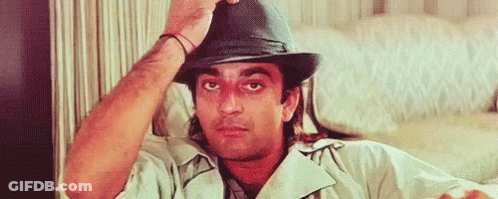 A Man Wearing A Hat Is Sitting On A Couch And Adjusting His Hat . GIF