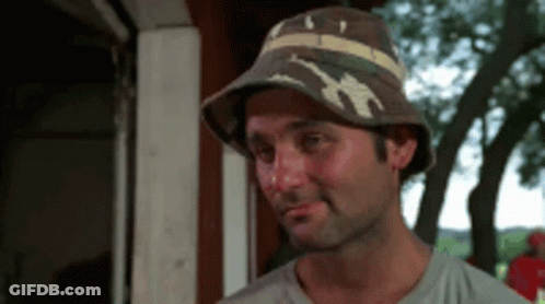 A Man Wearing A Hat Is Smiling And Looking At Something GIF