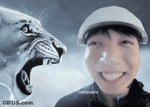 A Man Wearing A Hat Is Smiling In Front Of A Lion GIF