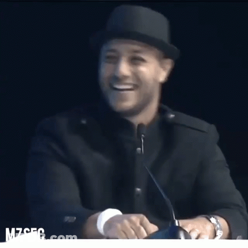 A Man Wearing A Hat Is Smiling In Front Of A Microphone With The Letters Mzsfc On The Bottom GIF
