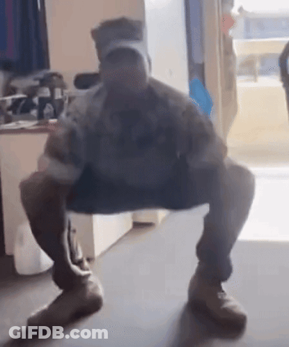 A Man Wearing A Hat Is Squatting Down In A Room . GIF