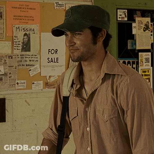 A Man Wearing A Hat Is Standing In Front Of A Bulletin Board With Missing And For Sale Signs On It GIF