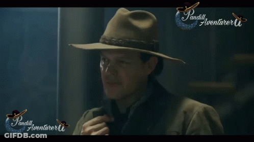 A Man Wearing A Hat Is Standing In Front Of A Sign That Says ' Pandill Aventurer ' GIF