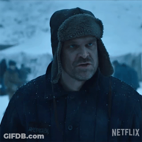 A Man Wearing A Hat Is Standing In The Snow With A Group Of People In The Background . GIF