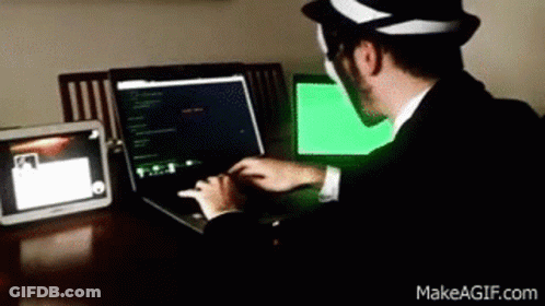 A Man Wearing A Hat Is Typing On A Laptop GIF