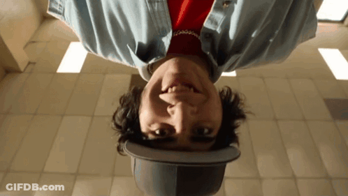A Man Wearing A Hat Is Upside Down And Looking At The Camera GIF