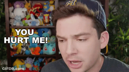 A Man Wearing A Hat Says " You Hurt Me " In Front Of A Shelf Full Of Stuffed Animals GIF