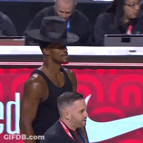 A Man Wearing A Hat Stands In Front Of A Red Nike Sign GIF
