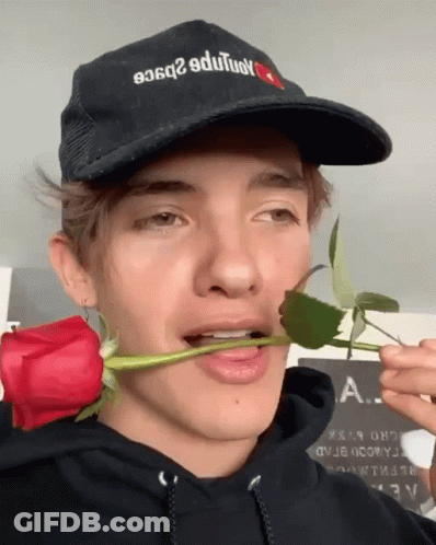 A Man Wearing A Hat That Says ' A. ' On It Is Holding A Rose In His Mouth GIF