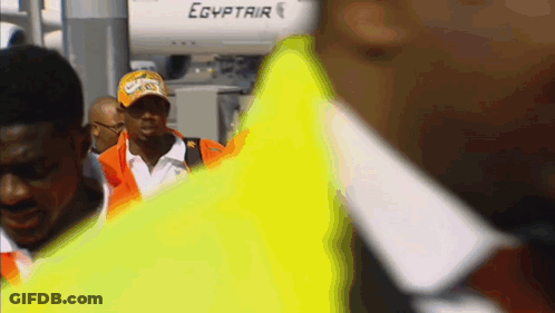 A Man Wearing A Hat That Says ' Egyptair ' On It Walks In Front Of An Airplane GIF