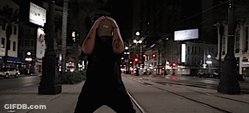 A Man Wearing A Hat That Says Ftp On It Stands On A City Street GIF