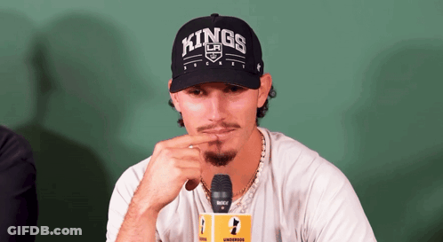 A Man Wearing A Hat That Says Kings Is Sitting In Front Of A Microphone GIF
