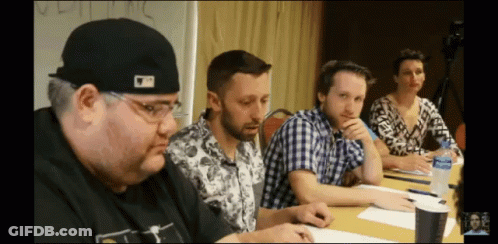 A Man Wearing A Hat That Says ' Mlb ' On It Sits At A Table GIF