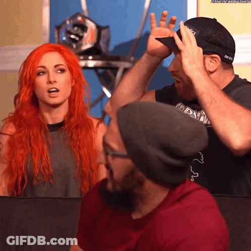 A Man Wearing A Hat That Says ' Nbc ' On It Stands Next To A Woman With Red Hair GIF