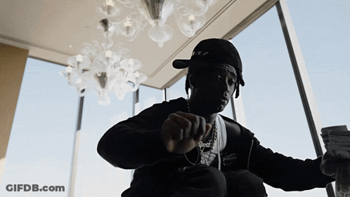 A Man Wearing A Hat That Says Ritz Is Holding A Stack Of Money GIF