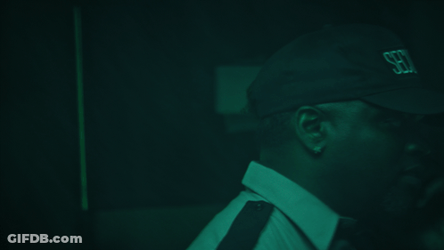 A Man Wearing A Hat That Says Security Is Talking On A Cell Phone GIF