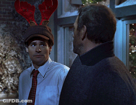 A Man Wearing A Hat With Reindeer Antlers Looks At Another Man GIF