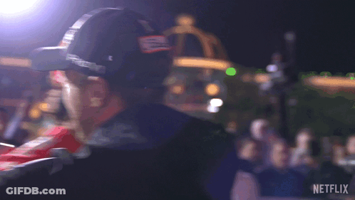 A Man Wearing A Hat With The Letter B On It Is Standing In Front Of A Crowd And A Sign That Says Netflix GIF