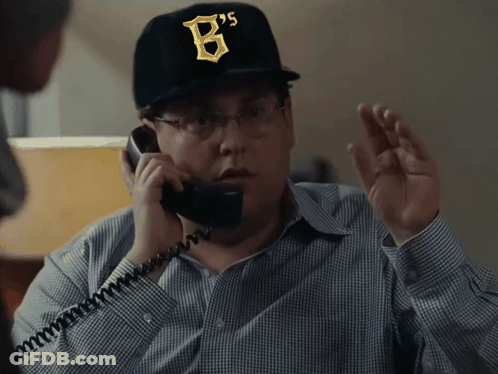 A Man Wearing A Hat With The Letter B On It Talks On A Phone GIF
